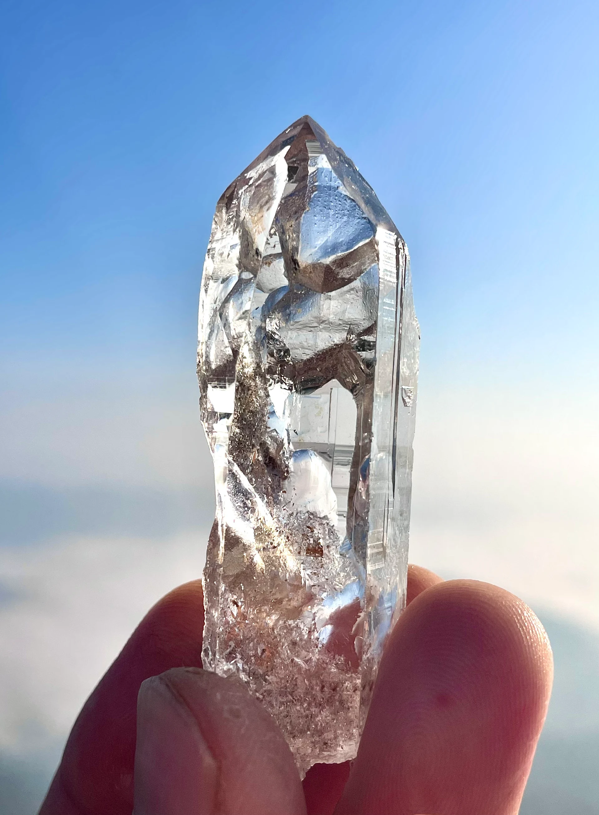 A natural crystal held against the blue sky